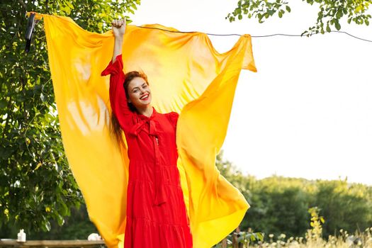 woman in a red dress with hands raised up yellow fabric nature. High quality photo