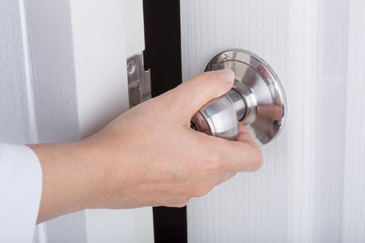 Hand opening door knob on the white door