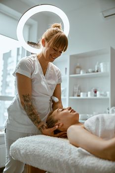 Adult female specialist is doing neck massage to a young natural beautyful female client