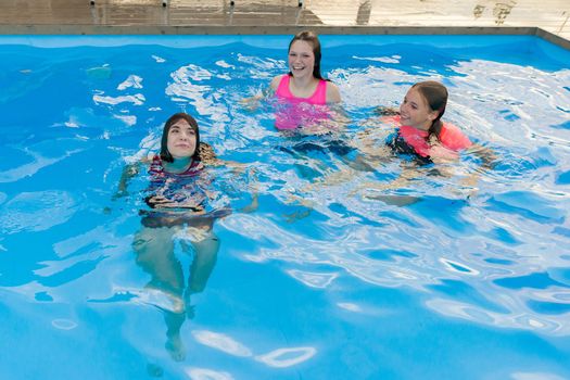 Group of 3 teenage girlfriends having fun in swimming pool