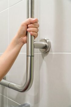 Woman holding on handrail in toilet.