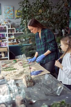 Flourist shop with different kinds of dryed flowers. Young happy confident specialist is working with her female kid.