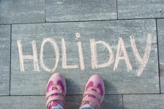 Word holiday written chalk and feet child.