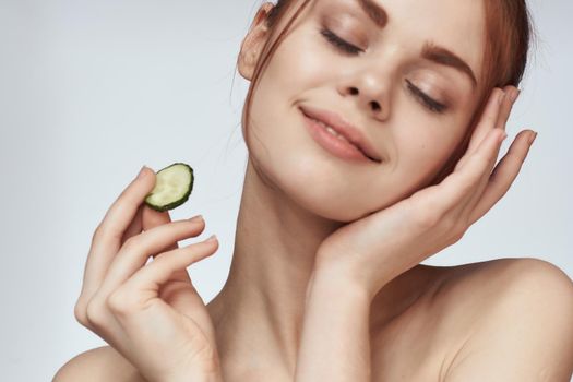 attractive woman with bare shoulders cucumber skin care health. High quality photo