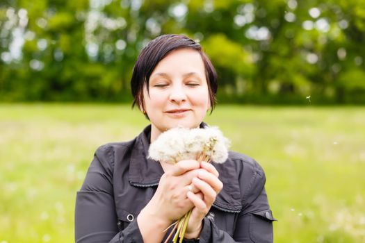 Girl blowing on white dandelion in the forest