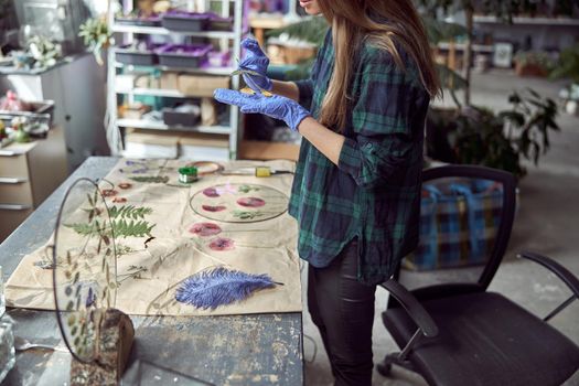 Confident female florist is working with dryed flowers in cozy flower shop