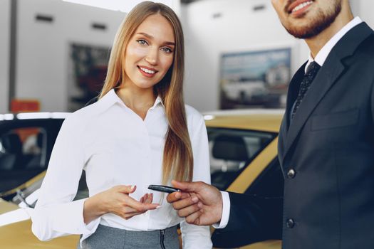 Young attractive woman buying a new car in car salon close up