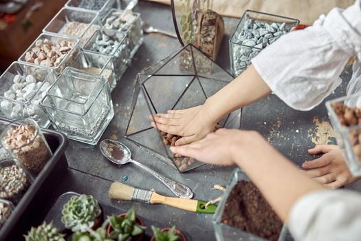 caucasian confident happy florist is working with composition made from glass stones and plants in botanic shop