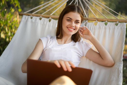 woman working in front of laptop in a hammock in nature. High quality photo