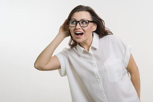 Woman listening to something holding hand near her ear. Curiosity concept, white background