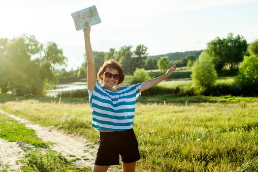 A woman is traveling. It stands on a country road and holds a road map