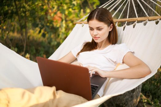woman with laptop lies in hammock freelance travel. High quality photo