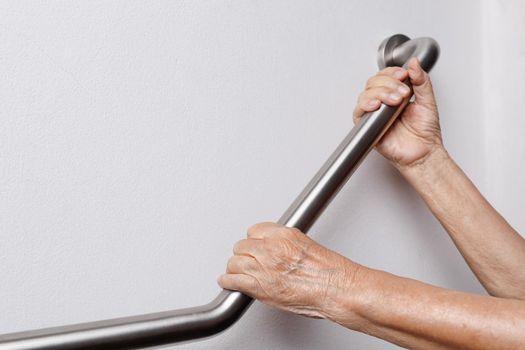 Elderly woman holding on handrail for safety walk steps