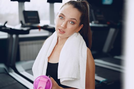 Young sporty woman having a drink in a gym after workout, close up