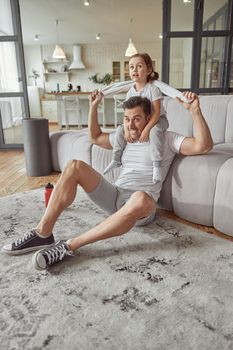 Jolly man is having fun with girl in living room while he is preparing for workout indoors