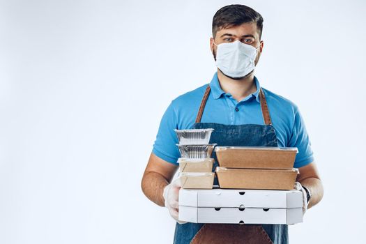 Delivery man in protective mask and medical gloves holding takeaway food. Compliance with the hygiene rules while covid-19 pandemic. Safe service