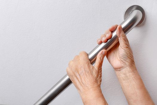 Elderly woman holding on handrail for safety walk steps