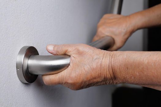 Elderly woman holding on handrail for safety walk steps