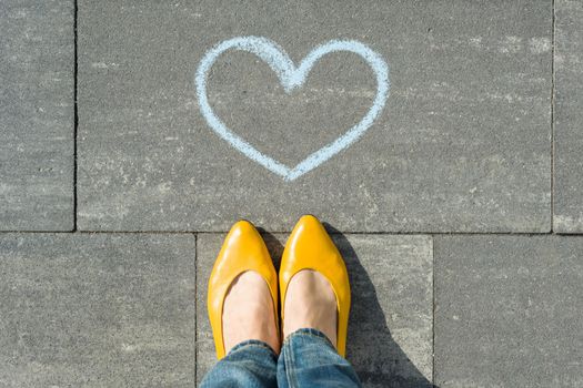 Female feet with symbol of the blue heart painted on the asphalt