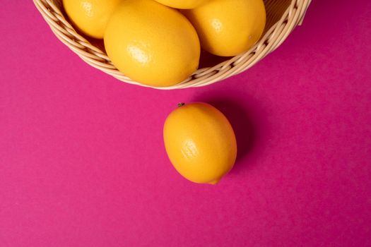 Ripe lemons on bright pink paper background. Close up.