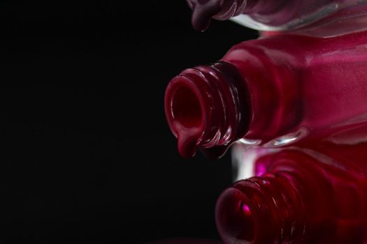 Background nail polish in a low key red burgundy pours flows out of the bottle with a copy of the place for text.