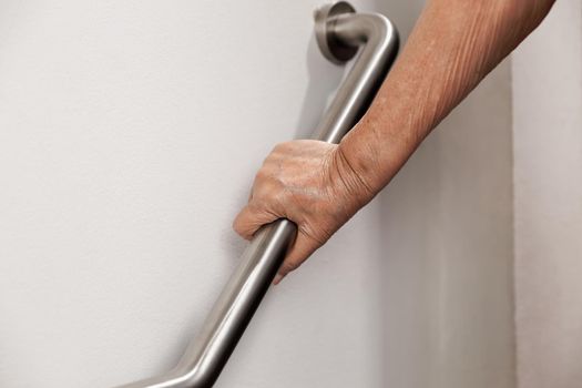 Elderly woman holding on handrail for safety walk steps