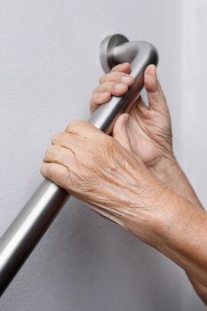 Elderly woman holding on handrail for safety walk steps