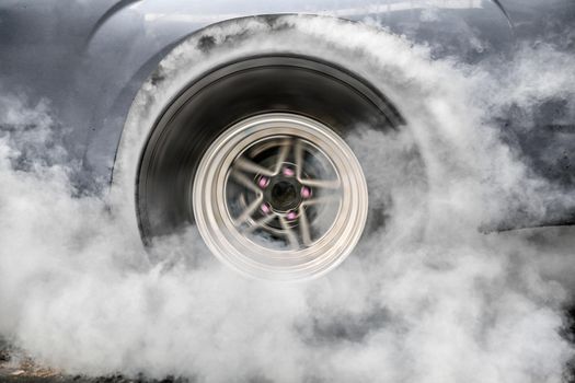 Drag racing car burns rubber off its tires in preparation for the race