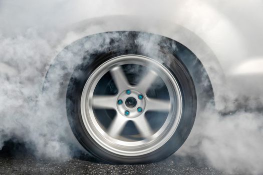 Drag racing car burns rubber off its tires in preparation for the race