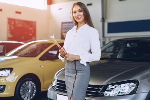 Happy beautiful young woman car dealer in showroom close up