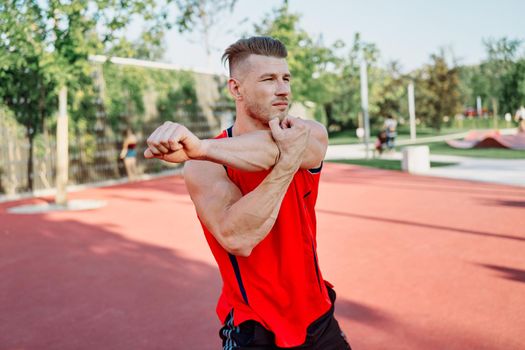 sports man in a red t-shirt on the sports ground doing exercises. High quality photo