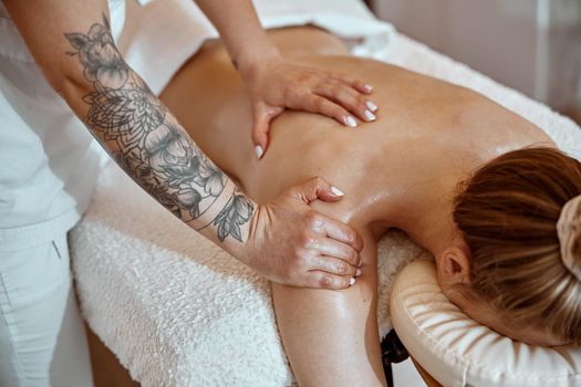 Professional confident massage master is doing procedures to caucasian woman in minimalistic modern cabinet