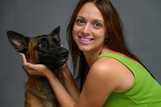 Portrait of a young woman posing playing with a Belgian shepherd dog in the studio