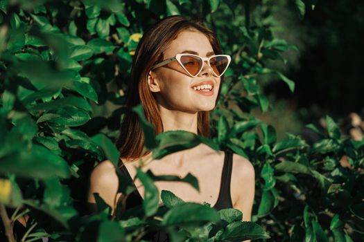 smiling woman wearing sunglasses green leaves nature fashion. High quality photo