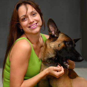 Portrait of a belgian shepherd dog playing with a cute smiling woman