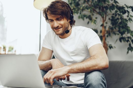 Young man businessman with headset working on laptop from home. Home office concept