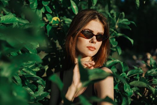 cheerful fashionable woman in sunglasses and green leaves summer luxury. High quality photo