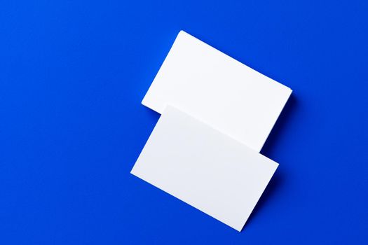 Blank white businesscards on classic blue background, copy space