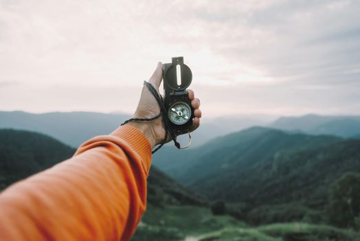 Man explorer searching direction with compass in summer mountains, point of view.