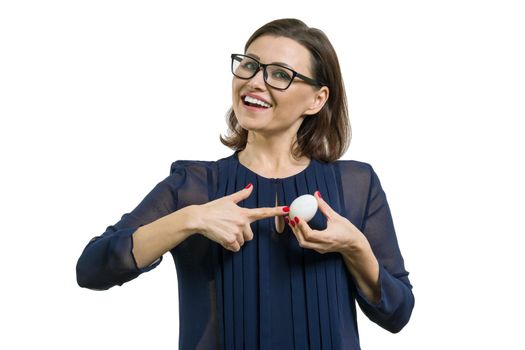Isolated portrait of an adult attractive woman pointing at white egg. The concept of start, success, start, business