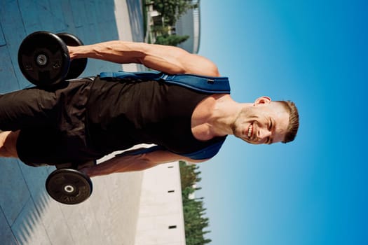 athletic man with dumbbells in his hands in the park training lifestyle. High quality photo