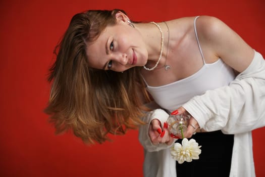 Smiling girl posing with flower in studio on red background