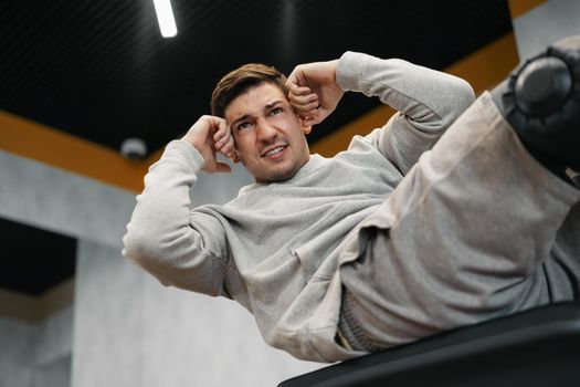 Young athlete doing abs exercises workout in modern gym, close up