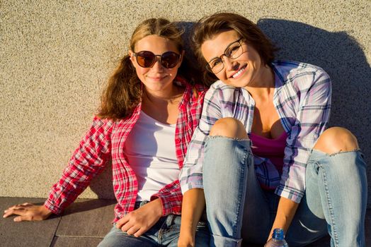 Happy loving family. Young mother and daughter teenager, hugging and smiling. Sunny day in the city