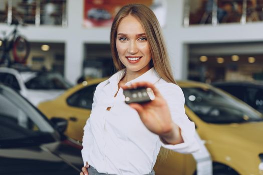 Young happy woman buyer/seller near the car with keys in hand close up