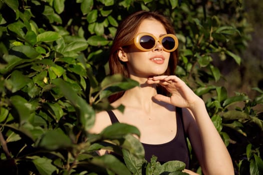 cheerful woman wearing sunglasses green leaves nature summer posing. High quality photo
