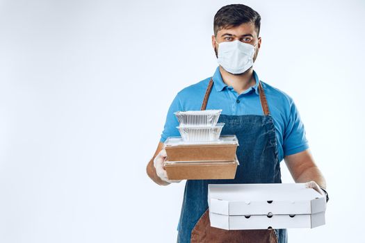 Delivery man in protective mask and medical gloves holding takeaway food. Compliance with the hygiene rules while covid-19 pandemic. Safe service