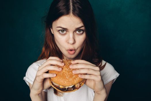 cheerful woman with hamburger near face snacking fast food. High quality photo