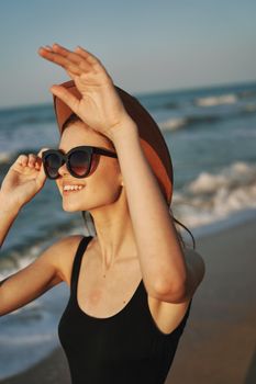 cheerful woman in sunglasses and a hat by the ocean walk summer. High quality photo