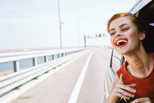 cheerful woman peeking out of the car window trip road travel. High quality photo